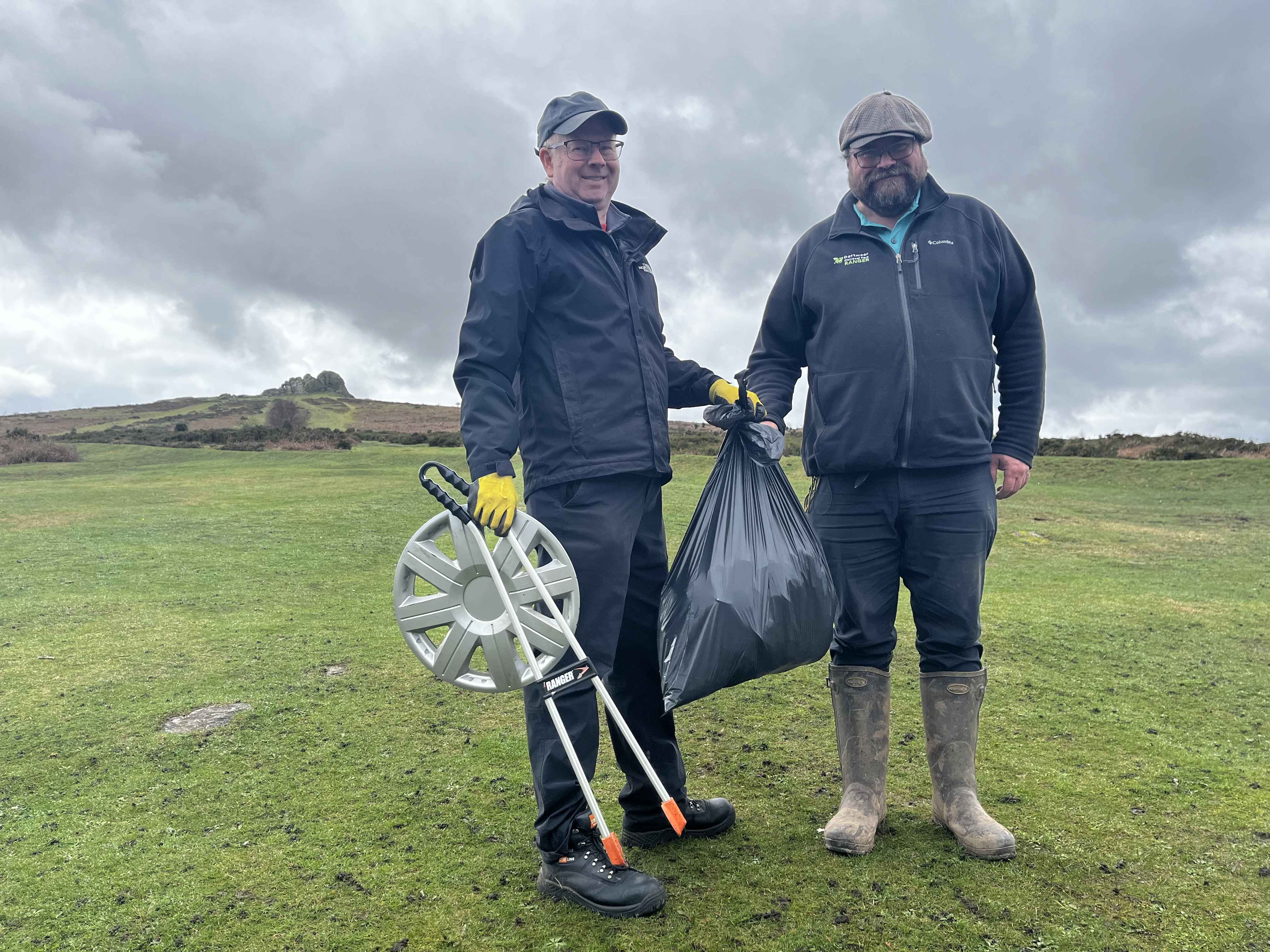 Litter picking volunteer Gian Ellis hands over a black bag full of litter to Dartmoor Ranger Bill Allen 