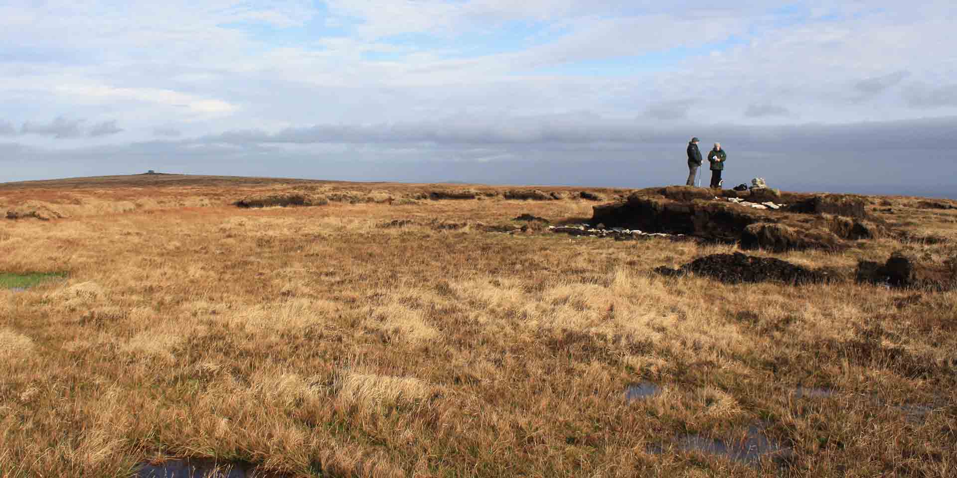 Boggy moorland and two people stood on Whitehorse Hill