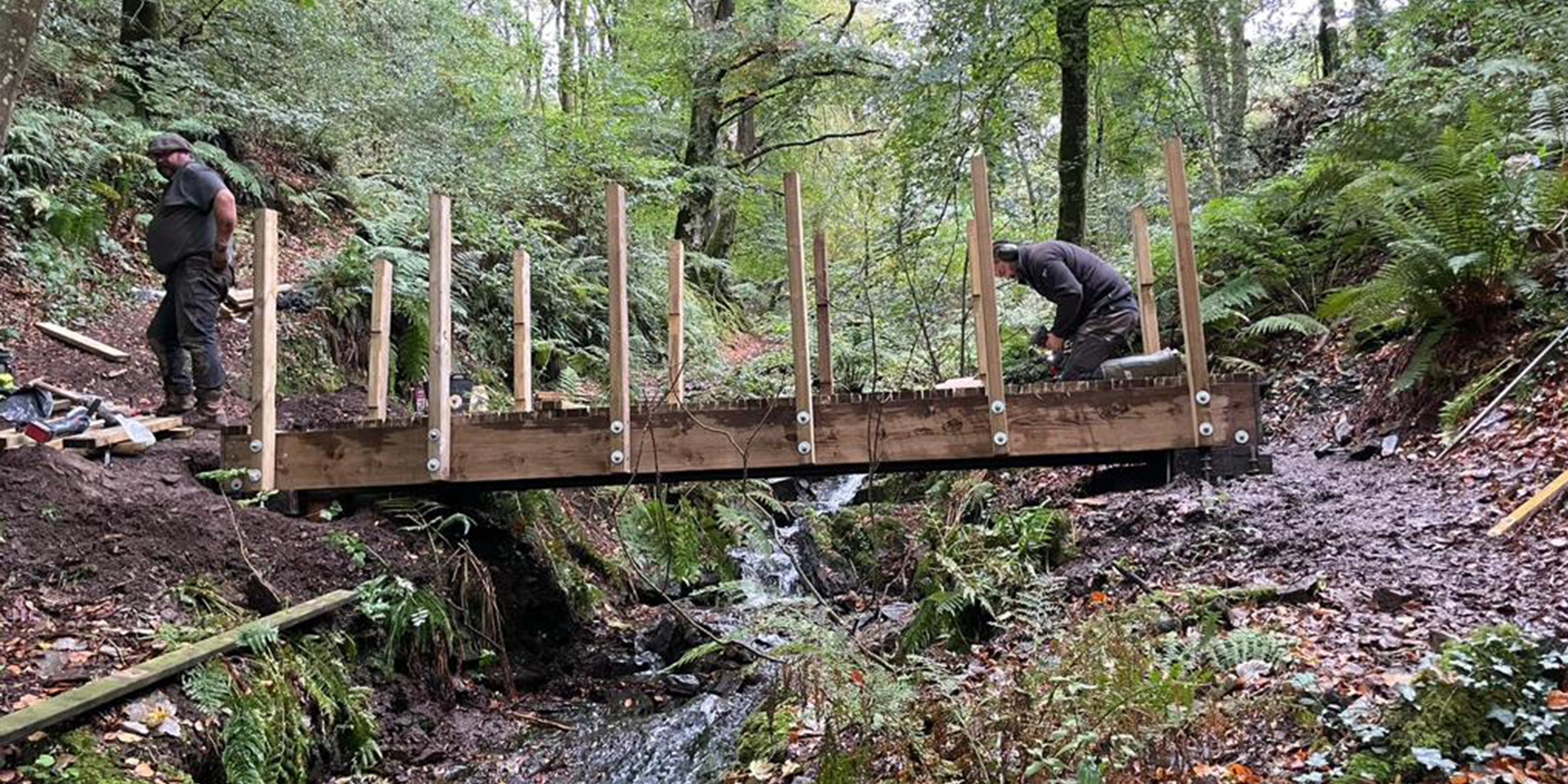 Bridge half built. Two rangers working on it. 