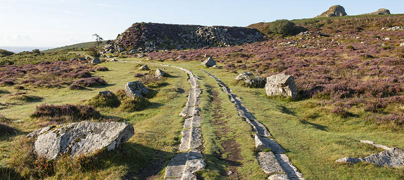 Granite tramway leading to large quarry heap covered in heather
