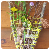 Y shaped stick wrapped in string and decorated with flowers and leaves