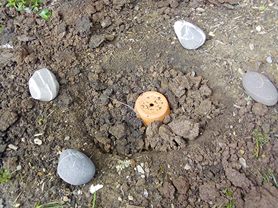 An upturned flower pot half buried in the ground