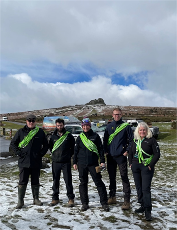 Rangers, volunteers, National Trust and Outreach team standing with haytor in the background on a snowy day, with the free leads around their chests