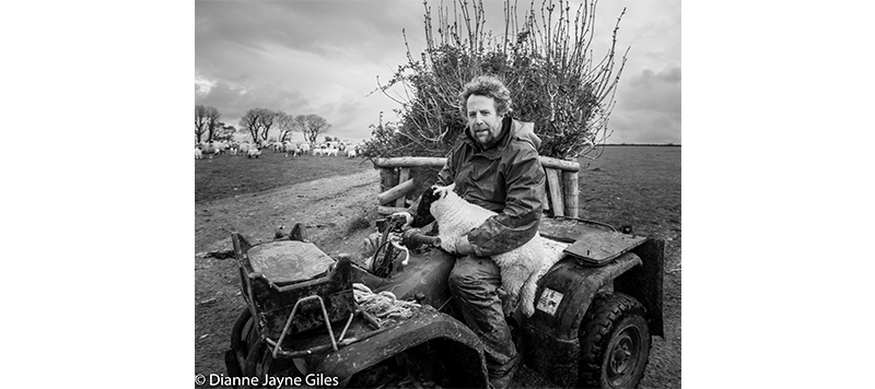 Farmer Mat Cole sat on a quad bike holding a lamb