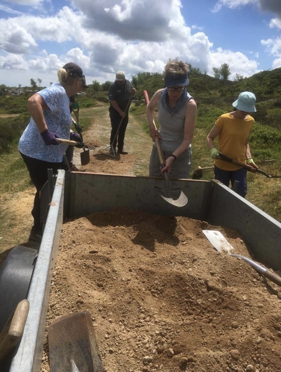 Volunteers spading sand from a trailer onto the ground at Haytor on Dartmoor