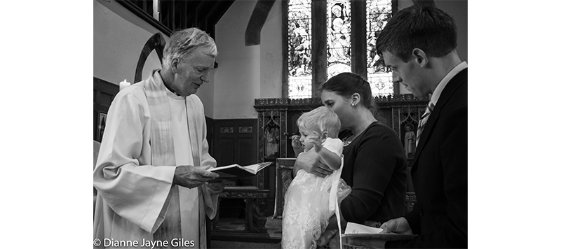 Vicar reading to baby and family at a christening