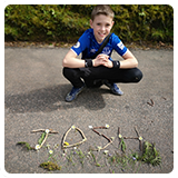 Boy smiling next to sticks spelling Josh