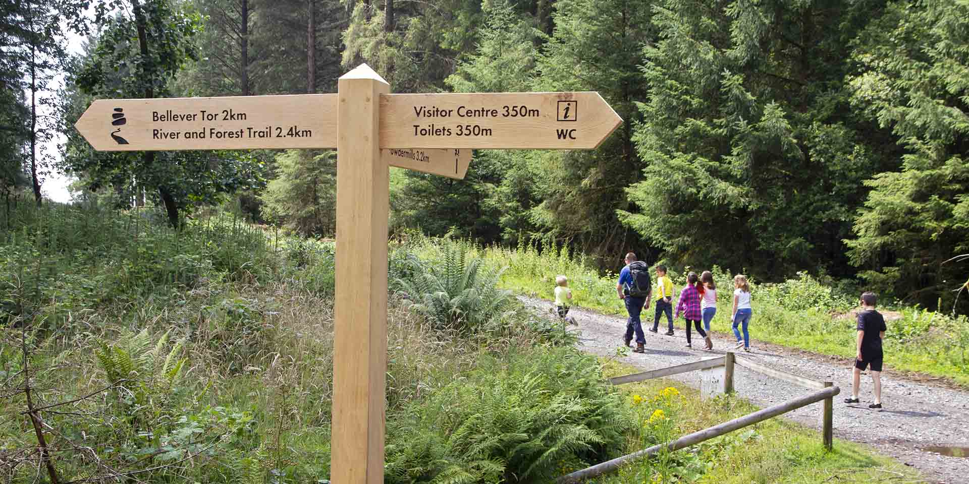 Timber signpost in forest directing to Bellever Tor and National Park Visitor Centre