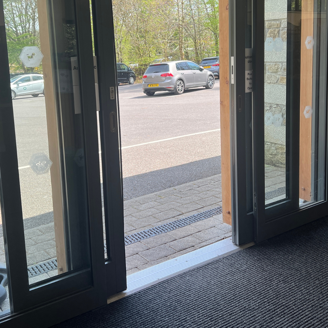 Entrance to the Postbridge Visitor centr from inside, looking out to the car parkl through open doors 