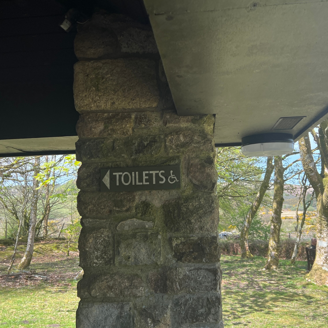 Sign on a stone pillar pointing to the toilets 