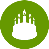 White birthday cake with five flaming candles inside a green circle