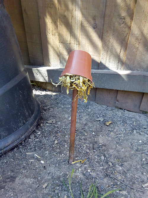 Upside down flower pot stuffed with straw on a stick
