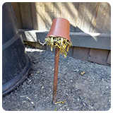 Upside down flower pot stuffed with straw on a stick