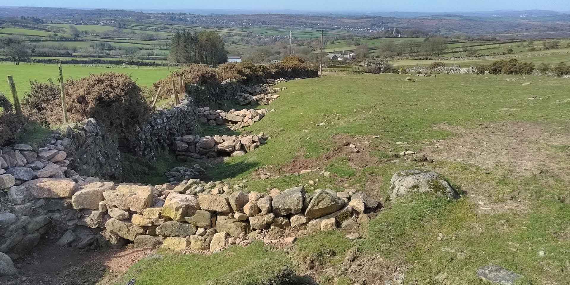 Stone dams built in drainage ditch next to stone wall