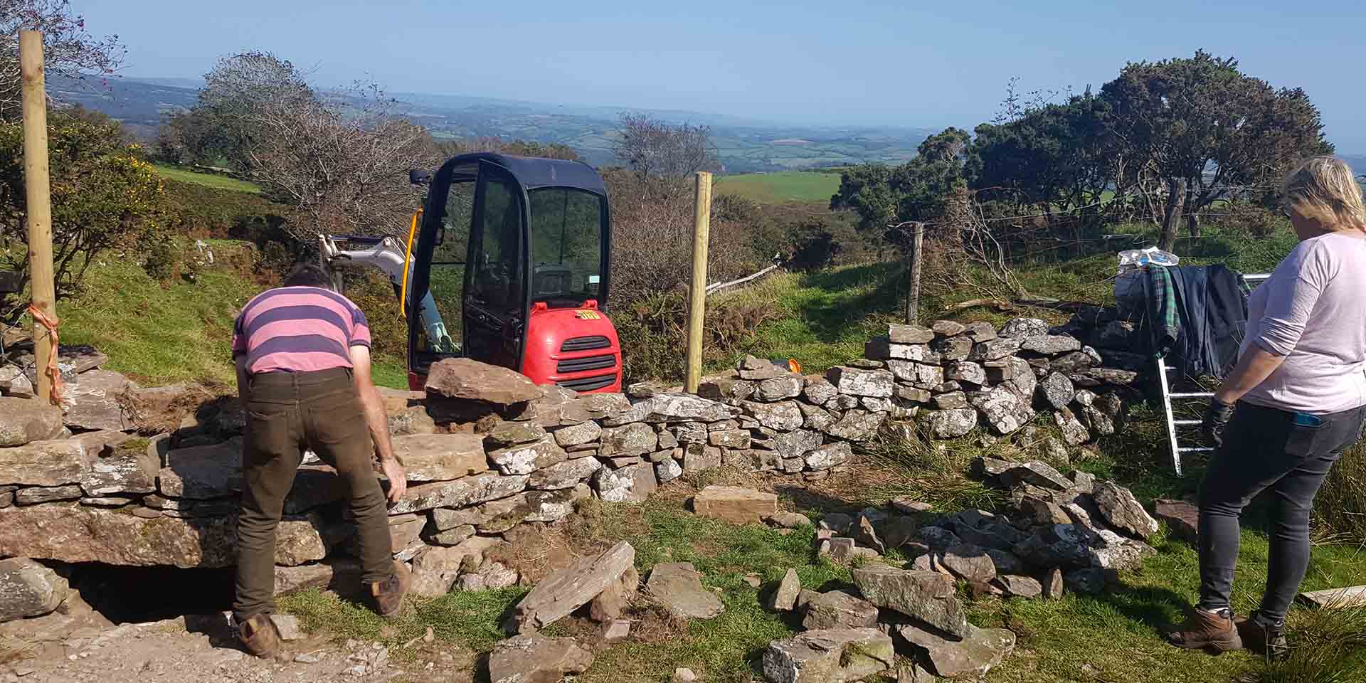 Contractors building a stone wall on moorland