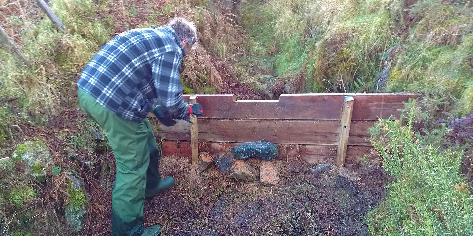 Person building a leaky dam out of timber planks