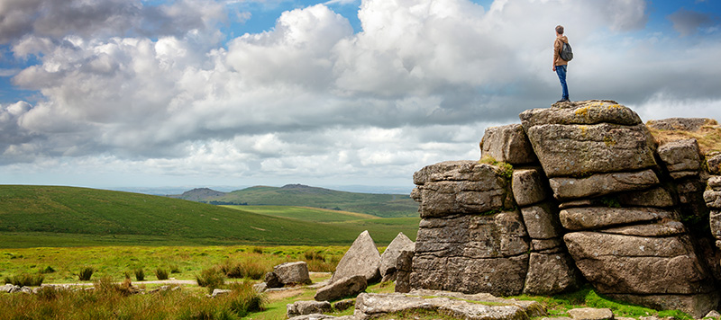 Walker stood on South Hessary Tor gazing at moorland view